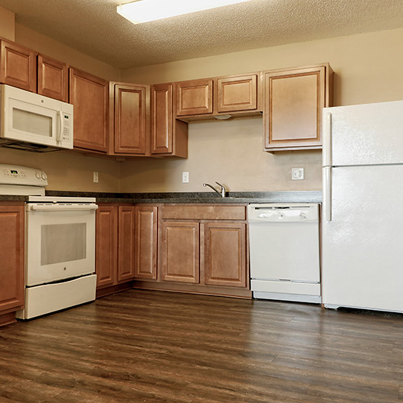 Kitchen with wooden cabinets, white appliances, and wood flooring