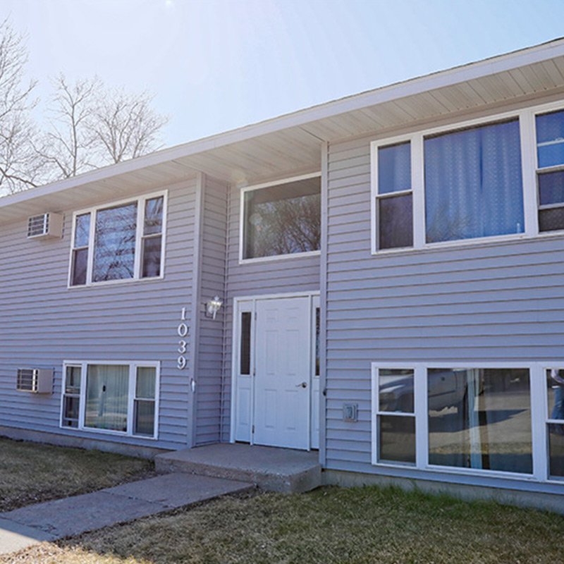 Two-story gray building with windows and a white door